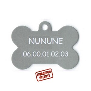 Peut inclure: Une étiquette grise en forme d'os pour animaux de compagnie avec le nom "NUNUNE" et un numéro de téléphone imprimé en blanc. L'étiquette a un trou pour l'attacher à un collier. Un tampon rouge avec le texte "LIVRAISON OFFERTE" est visible.