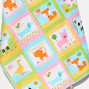 May include: A colorful baby quilt with a patchwork design featuring various animals, including a fox, cat, dog, sheep, duck, and panda. The quilt is made with a variety of fabrics in shades of pink, blue, yellow, and green.