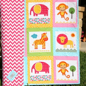 May include: A colorful baby quilt with a pink, yellow, and blue background. The quilt features a variety of animal designs, including elephants, monkeys, zebras, and lions. The quilt is made of soft, comfortable fabric and is perfect for a baby's nursery.