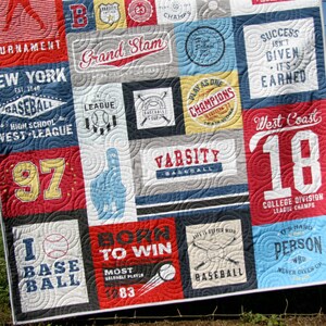 May include: A colorful quilt with a baseball theme. The quilt is made up of different squares with various baseball-related designs, including text, logos, and images. Some of the text on the quilt includes "Grand Slam", "New York", "West Coast", "Varsity Baseball", "Born to Win", and "I Love Baseball".