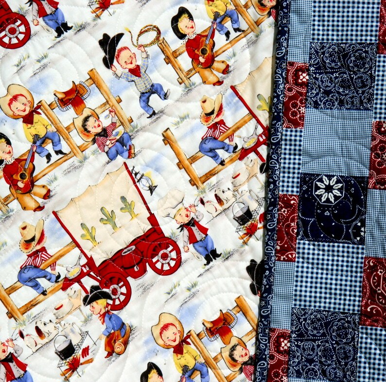 May include: A white quilt with a patchwork design featuring cowboys and a wagon. The quilt is made of cotton fabric and has a blue and red checkered backing.