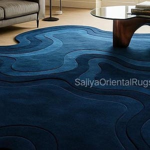 Custom-sized deep blue hand-tufted rug partially rolled to show backing and craftsmanship, with visible wool pile and sturdy construction