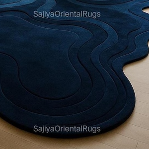Overhead view of hand-tufted deep blue wool rug in a freeform, organic shape; photographed against a clean white background to highlight the design.