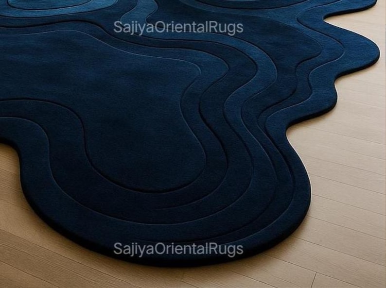 Overhead view of hand-tufted deep blue wool rug in a freeform, organic shape; photographed against a clean white background to highlight the design.