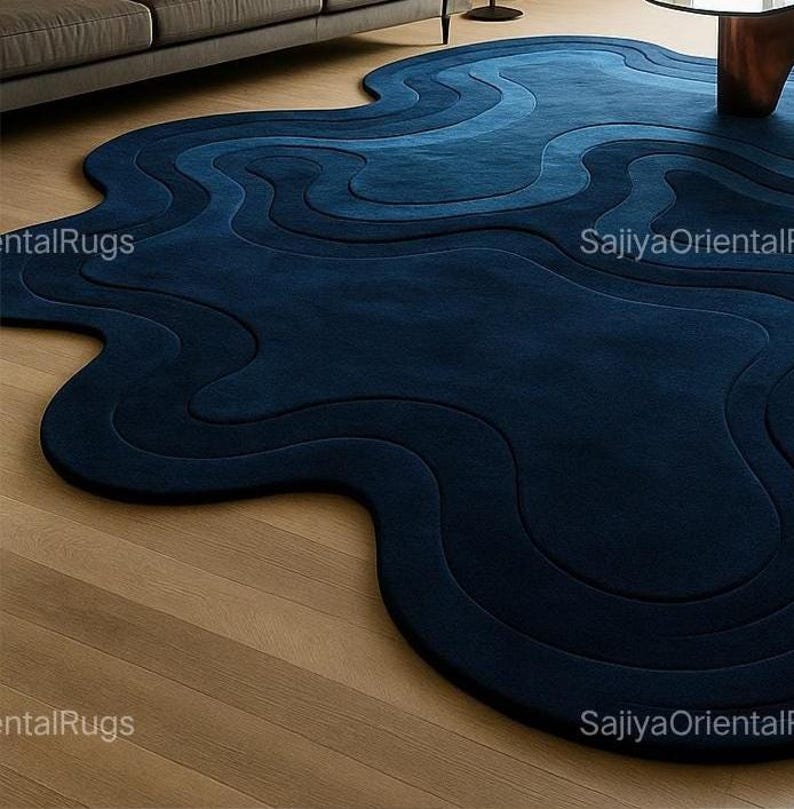 Deep blue abstract rug with irregular edges placed in a modern kids room with a white crib, wooden toys, and colorful wall art