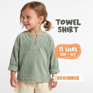 May include: A sage green long-sleeve shirt made of textured towel fabric with a small button-up placket at the neckline. The image includes text that reads TOWEL SHIRT, 11 sizes 12M - 16Y, and BEGINNER. The shirt has cuffed sleeves and a loose fit.
