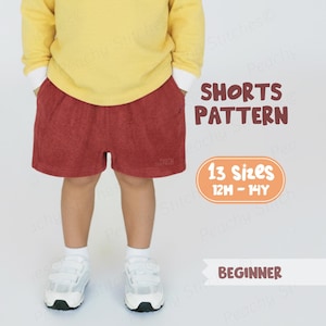 Op de afbeelding: Een kind draagt een gele top en een rode short. Het shortpatroon is verkrijgbaar in 13 maten, van 12 maanden tot 14 jaar, en is geschikt voor beginners. De tekst "SHORTS PATTERN" wordt in bruin weergegeven.