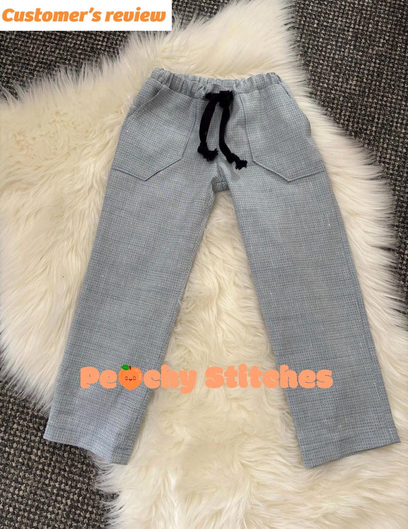 Op de afbeelding: Lichtblauwe broek met een subtiel ruitpatroon, voorzien van een elastische tailleband met een zwart trekkoord, twee voorzakken en een rechte pijp. De tekst "Customer's review" en "Peachy Stitches" met een perzik-icoon zijn zichtbaar.