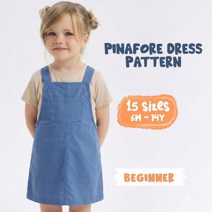 Könnte beinhalten: Ein junges Mädchen trägt ein blaues Latzkleid über einem beigen T-Shirt. Das Bild enthält den Text "Pinafore Dress Pattern", "15 Größen 6M-14Y" und "Beginner". Das Kleid hat eine Vordertasche und verstellbare Träger.