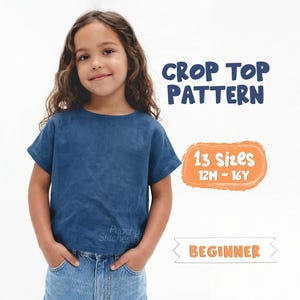 May include: A young girl wearing a blue crop top and denim shorts. The image includes text that reads "Crop Top Pattern", "13 Sizes 12M - 16Y", and "Beginner". The crop top is a solid blue color.
