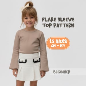 May include: A young girl wearing a beige long-sleeved top with flared sleeves and a white skirt with black pocket details. The image includes text that reads "FLARE SLEEVE TOP PATTERN", "15 Sizes 6M - 15Y", and "BEGINNER".
