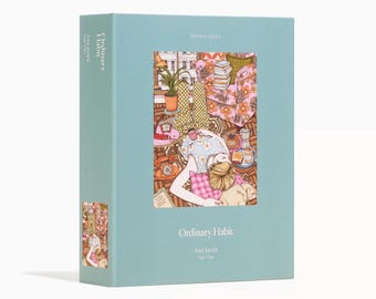 Könnte beinhalten: Eine hellblaue Puzzlebox mit dem Titel "Ordinary Habit" von Ana Jaren. Die Box zeigt eine Illustration einer Person, die sich in einem Raum mit einem floral gemusterten Stuhl und Büchern entspannt. Das Puzzle enthält 500 Teile.