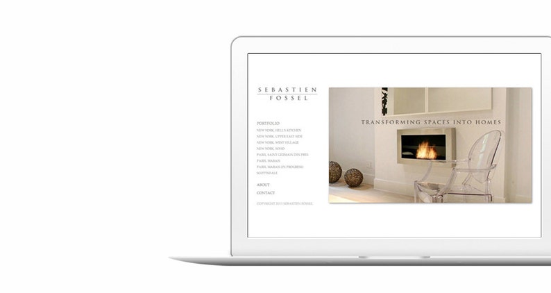 May include: A laptop computer displaying a website for interior designer Sebastien Fossel. The website features a white background with black text and a photo of a modern living room with a fireplace and a clear plastic chair. The text on the website reads "Transforming Spaces into Homes".
