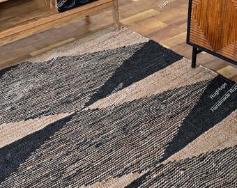 May include: A geometric area rug with a woven texture. The rug features diagonal stripes in black and tan. The rug is placed on a hardwood floor, with a wooden cabinet and wine rack visible in the background.