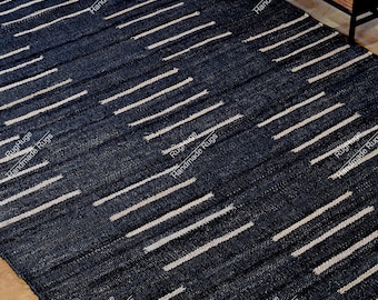 May include: A rectangular area rug featuring a deep navy blue base with a repeating pattern of horizontal, off-white dashed lines. The rug has a textured, woven appearance with visible fibers throughout the surface, creating a consistent design.