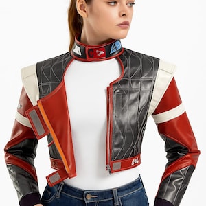 May include: A cropped, multi-colored leather jacket with a futuristic design. The jacket features a black quilted body, red sleeves, and white accents. The collar has colorful patches. The jacket is zipped up and has a unique, angular cut.