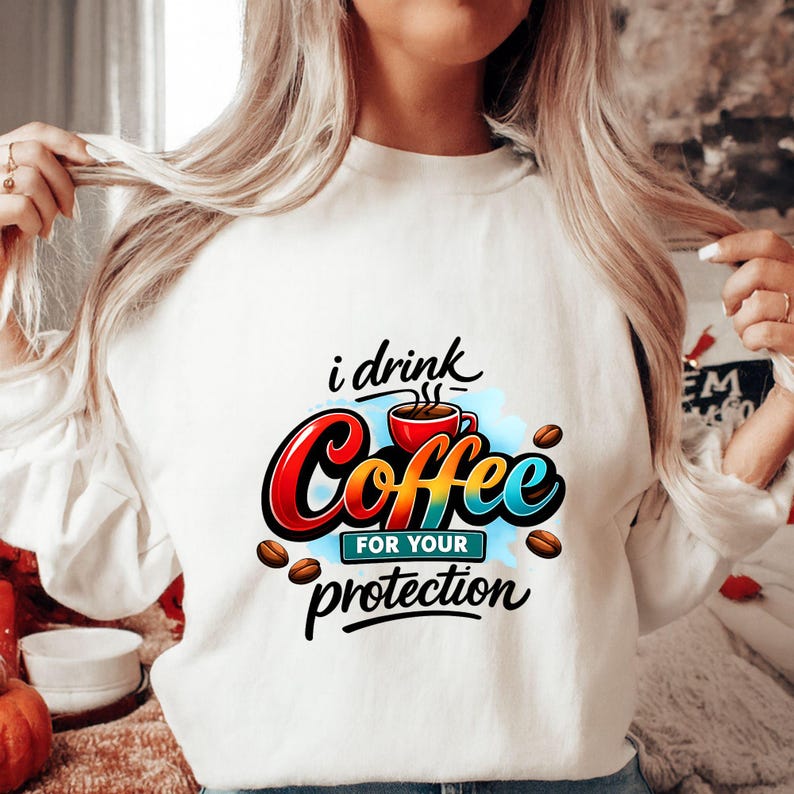 May include: White sweatshirt with the text "i drink Coffee for your protection" in a colorful design. The graphic includes a red coffee cup, coffee beans, and a blue cloud-like shape. A casual, everyday top.