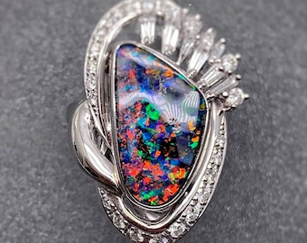 May include: A silver ring with a large, colorful opal gemstone set in a delicate, swirling design. The ring is accented with small, clear diamonds.