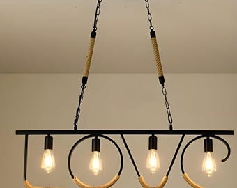 Peut inclure: Un lustre en métal noir épelant le mot "LOVE" avec des ampoules apparentes. Les lettres sont accentuées de corde et suspendues au plafond par des chaînes et des supports enveloppés de corde. Les ampoules sont allumées.