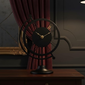 A black metal desk clock with a round face and Roman numeral hour markers. The clock has a globe-like frame and gold-colored hands. It sits on a dark wooden surface.