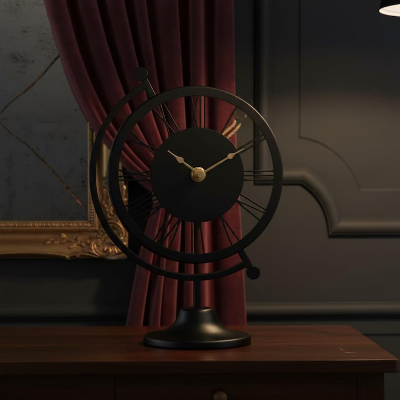 A black metal desk clock with a round face and Roman numeral hour markers. The clock has a globe-like frame and gold-colored hands. It sits on a dark wooden surface.