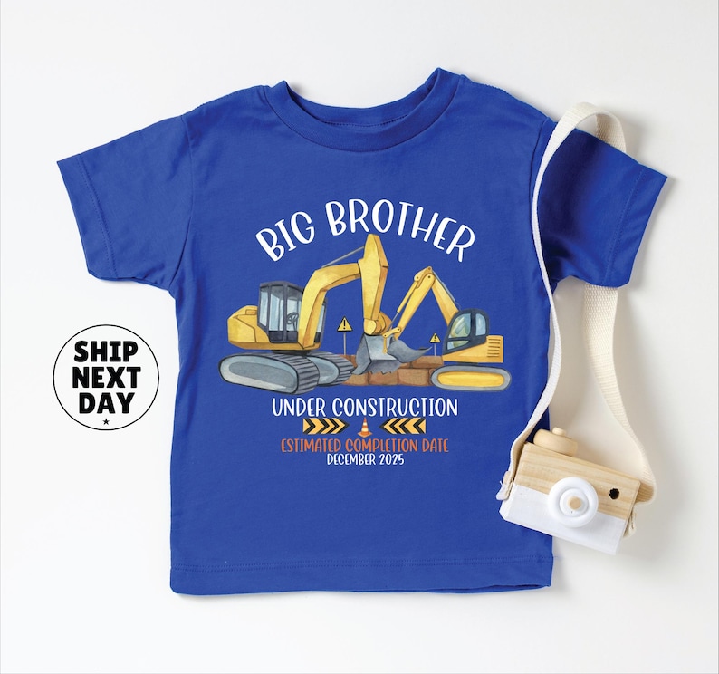 A blue t-shirt with a graphic design depicting construction equipment and the text "BIG BROTHER UNDER CONSTRUCTION ESTIMATED COMPLETION DATE DECEMBER 2035" printed on it.