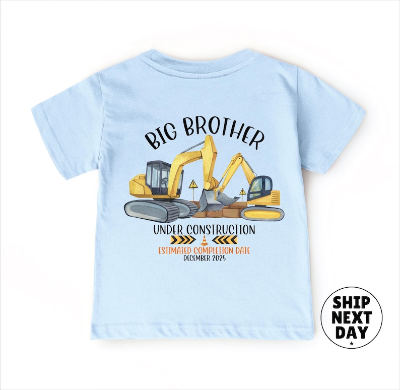 A light blue t-shirt with a graphic design depicting construction equipment and the text "BIG BROTHER UNDER CONSTRUCTION ESTIMATED COMPOSITION DATE December 2015".