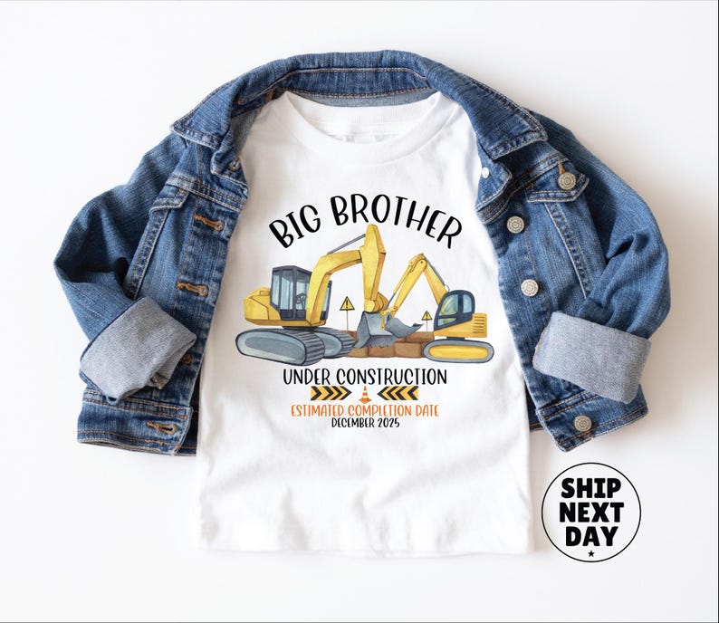 a white t-shirt with a graphic design depicting construction equipment and the text "BIG BROTHER UNDER CONSTRUCTION ESTIMATED COMPLETION DATE DECEMBER 2025". The t-shirt is placed on top of a denim jacket, and there is a shipping label next to it.