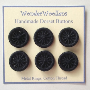 May include: Six black Dorset buttons arranged in two rows of three on a cream-coloured card. The text on the card reads WonderWoollens, Handmade Dorset Buttons, and Metal Rings, Cotton Thread. Each button features a circular metal ring frame.