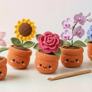Pode incluir: Uma coleção de cinco vasos de flores de crochê, cada um com uma flor diferente: um lírio rosa, um girassol amarelo, uma rosa vermelha, orquídeas roxas e uma hortênsia azul. Os vasos laranja têm rostos sorridentes. Há também uma agulha de crochê de madeira.