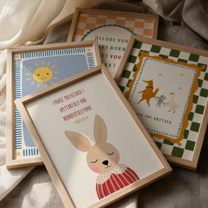 May include: A collection of framed art prints with light wood frames. The prints feature illustrations of a smiling sun, a bunny, and other whimsical designs. One print has the text "I PRAISE YOU BECAUSE I AM FEARFULLY AND WONDERFULLY MADE".