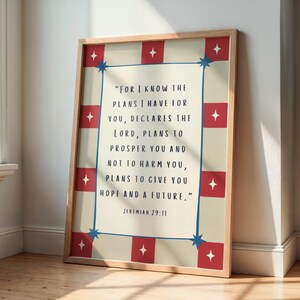 May include: A framed print with a light beige background and a quote in black text. The frame has a red and white starburst design. The quote reads, "For I know the plans I have for you..." from Jeremiah 29:11.