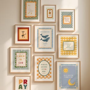 May include: A collection of framed art prints with various illustrations and text. The prints feature images of a goose, a bear, a guitar-playing figure, whales, a sun and moon, and text that reads "Child of God", "Pray", and other inspirational quotes. The frames are light wood.