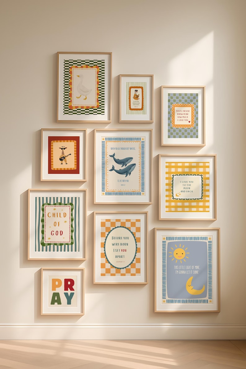 May include: A collection of framed art prints with various illustrations and text. The prints feature images of a goose, a bear, a guitar-playing figure, whales, a sun and moon, and text that reads "Child of God", "Pray", and other inspirational quotes. The frames are light wood.