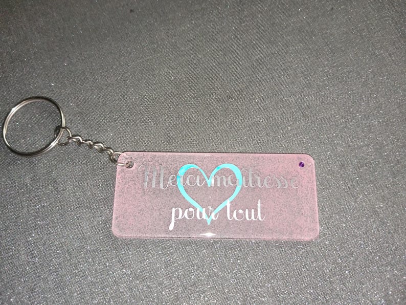 Peut inclure: Porte-cl&eacute;s rectangulaire rose avec un porte-cl&eacute;s et une cha&icirc;ne argent&eacute;s. Le porte-cl&eacute;s porte les mots "Merci ma&icirc;tresse pour tout" en blanc et un motif de c&oelig;ur turquoise.