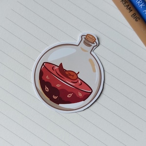May include: A sticker of a potion bottle with a cork stopper. The clear bottle contains a red liquid and a leaf. The potion is in a decorative bowl with leaf designs.