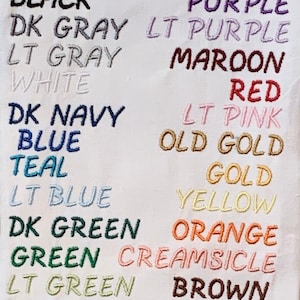 May include: A white fabric swatch with a list of colors and their names embroidered in different colored threads. The colors include black, dark gray, light gray, white, dark navy, blue, teal, light blue, dark green, green, light green, seacrest, purple, light purple, maroon, red, light pink, old gold, gold, yellow, orange, creamsicle, brown, and khaki.