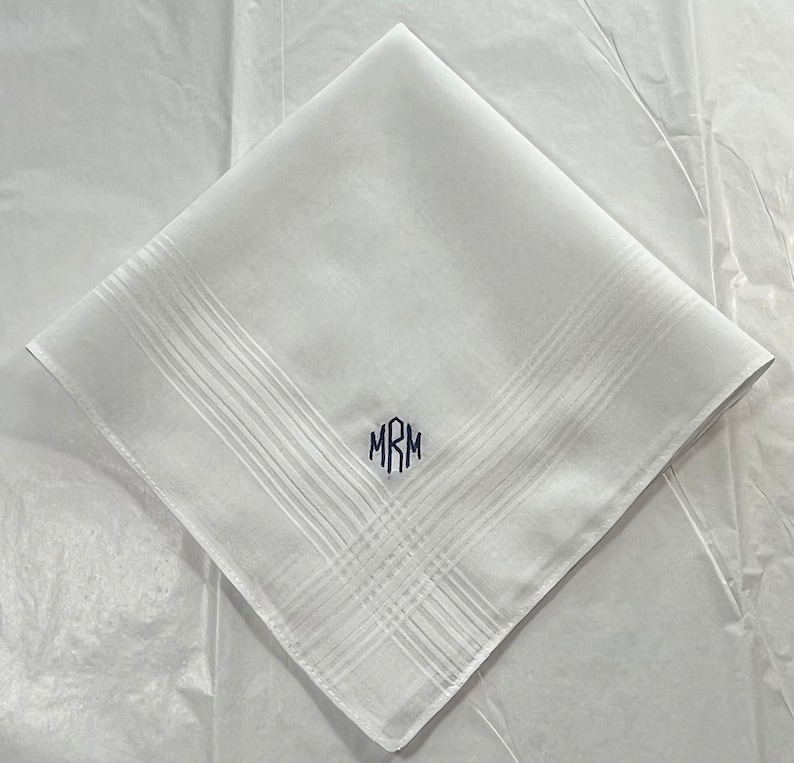 May include: White linen handkerchief with a monogram of the initials "MRM" embroidered in navy blue.