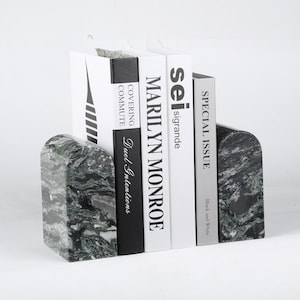 May include: A pair of marble bookends in shades of gray and green, holding several books. The bookends have a rounded top and a marbled pattern. The books include titles like "Marilyn Monroe" and "Special Issue."