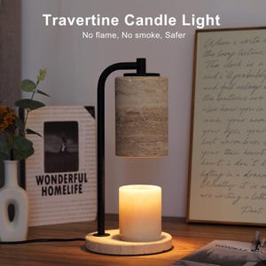 Op de afbeelding: Een kaarsverwarmerlamp van zwart metaal met een cilindrische beige travertijn stenen kap en een bijpassende ronde travertijn voet. Een witte waskaars staat op de voet en wordt verlicht door de lamp. Tekst Travertine Candle Light is zichtbaar.