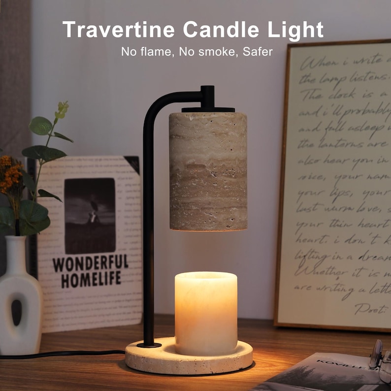 Op de afbeelding: Een kaarsverwarmerlamp van zwart metaal met een cilindrische beige travertijn stenen kap en een bijpassende ronde travertijn voet. Een witte waskaars staat op de voet en wordt verlicht door de lamp. Tekst Travertine Candle Light is zichtbaar.