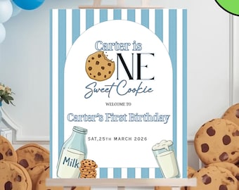 May include: A birthday party sign with the text "Carter is ONE Sweet Cookie" and "Carter's First Birthday". The sign is on an easel, surrounded by cookies and a balloon arch. The sign also says "SAT, 25TH MARCH 2026".