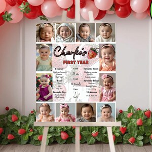 May include: A first birthday photo display featuring a collage of baby photos, a strawberry theme, and the text "Charlie's First Year." The display is set against a backdrop of red and pink balloons and strawberry decorations.