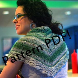 May include: A woman wearing a green and blue knitted shawl with a lace border. The shawl has a pattern of leaves and flowers. The text "Pattern PDF!" is superimposed on the image.