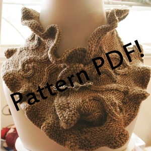 Pode incluir: Um cachecol de malha castanho com uma borda franjada. O cachecol é apresentado em um manequim branco. O texto "Pattern PDF!" é sobreposto à imagem.