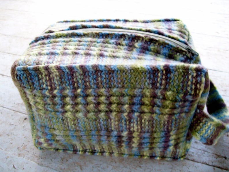 May include: A knitted zippered pouch with a green, blue, and brown pattern.
