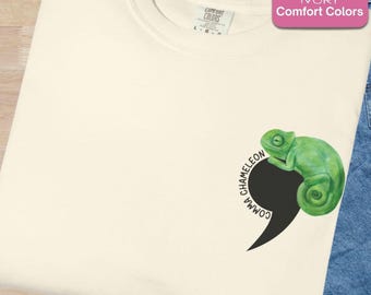 Puede incluir: Sudadera marfil Comfort Colors con un diseño de camaleón verde. El camaleón está sobre una coma negra, con las palabras "comma" y "chameleon" en un diseño circular.