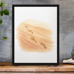 May include: Framed art print featuring a watercolor illustration of footprints in the sand. The artwork has a neutral color palette with shades of tan and brown, and is set against a white background. The black frame adds a modern touch.