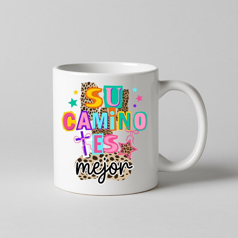 Peut inclure: Mug en c&eacute;ramique blanche avec un motif color&eacute;. Le motif pr&eacute;sente les mots "SU CAMINO ES mejor" dans diff&eacute;rentes couleurs et polices, avec un fond &agrave; imprim&eacute; l&eacute;opard et des &eacute;toiles. La tasse a une anse incurv&eacute;e.