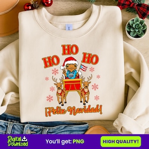 May include: A cream-colored sweatshirt with a festive Christmas design. The graphic features a frog wearing a Santa hat and holding a Puerto Rican flag, riding a sleigh pulled by reindeer. The words "HO HO HO" and "¡Feliz Navidad!" are displayed in red.